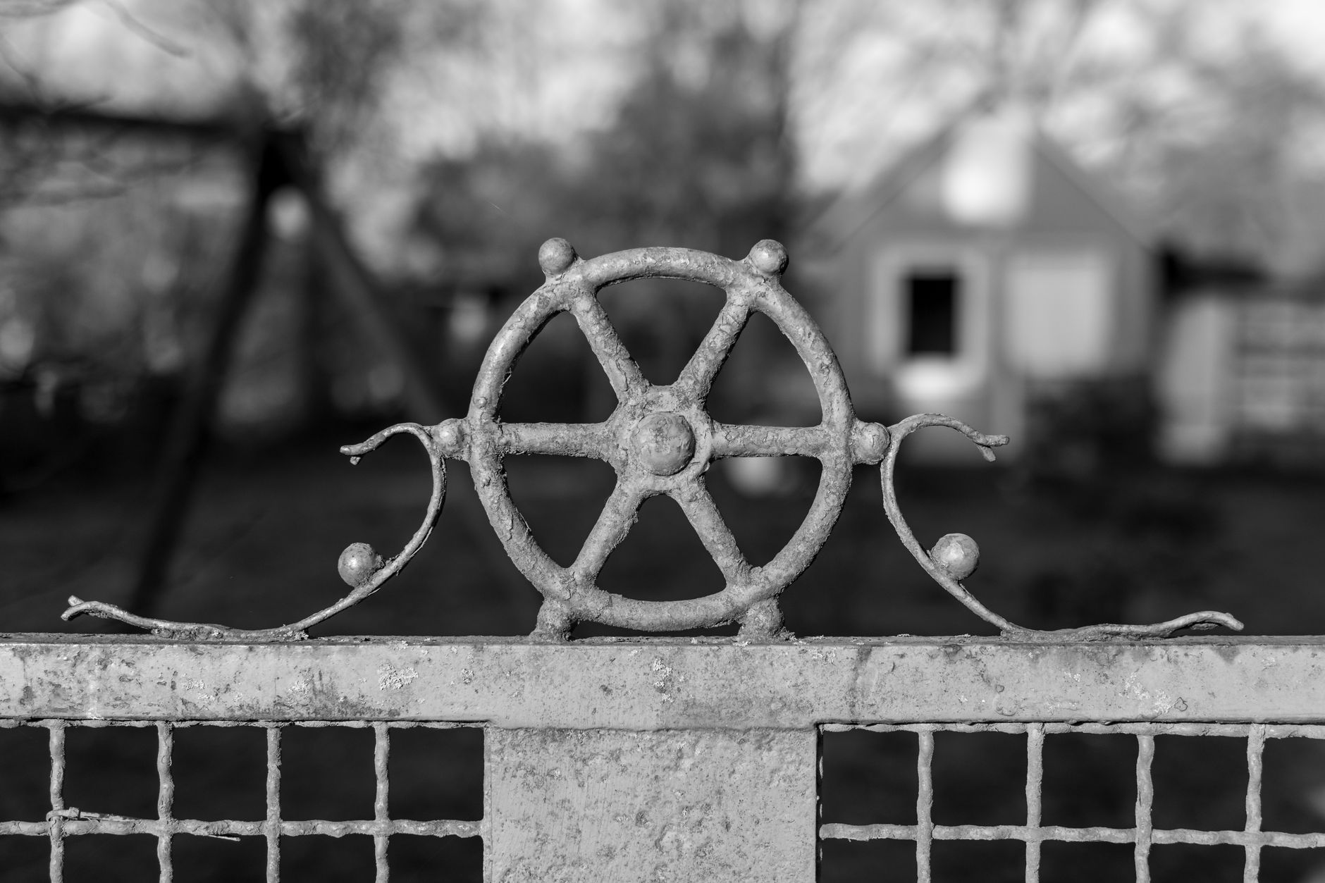 Rustic black metal ornament on a gate, shown in black and white